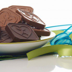 Bowl of IsaDelight squares next to blue and green ribbon