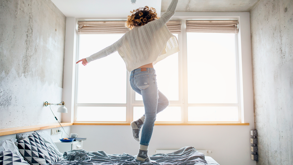 Woman jumping on bed