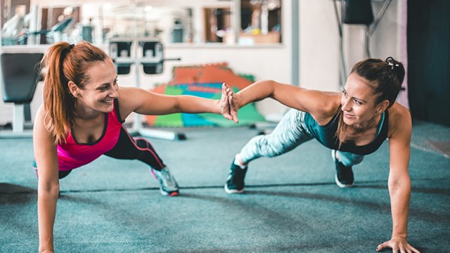 Two women doing pushups together and high-fiving