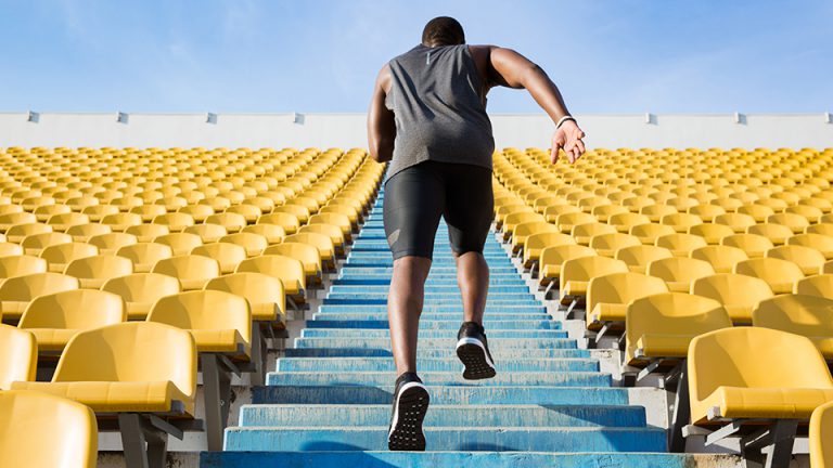 Man running up blue stairs surrounded by bright yellow stadium seats