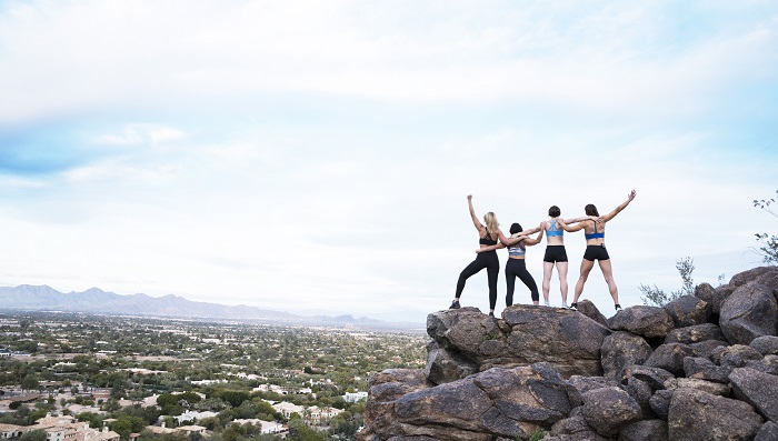 Group of IsaBody Challenge finalists standing on top of a mountain with their arms in the air