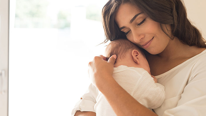 Happy mother cradles her baby to her chest