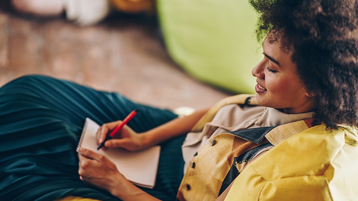 Woman in a yellow jacket journaling on a notepad