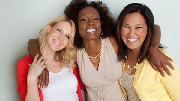 Three smiling women with their arms around each other