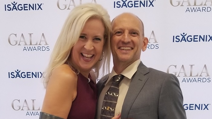 Husband and wife Brent and Tracey Shaw smiling in front of the Isagenix Gala Awards wall - wellness routine