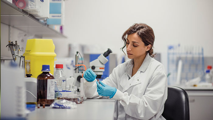 Woman in a lab testing a bottle.