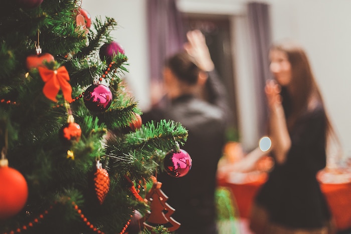 A close-up of a Christmas tree with holiday guests in the background