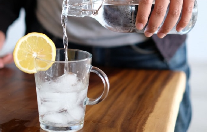 Hand pouring glass of lemon water