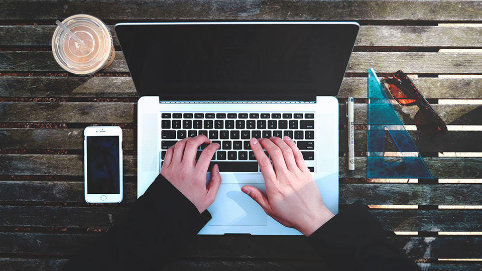 Hands typing on a laptop