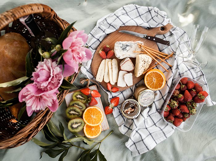 Charcuterie board with cheese, fruit, and flowers