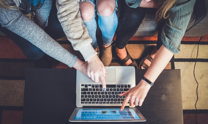 An aerial shot of three women pointing at a laptop screen