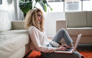 Woman working on her laptop on the floor of her living room