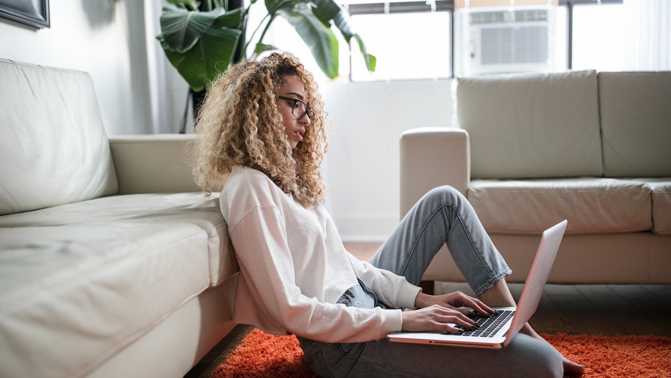 Woman working on her laptop on the floor of her living room