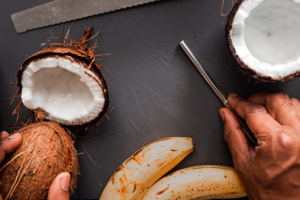 A man's hands preparing coconuts and bananas