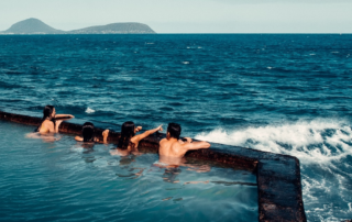 Four people swimming by the ocean