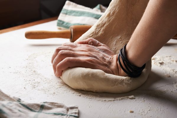 Hands kneading dough on counter