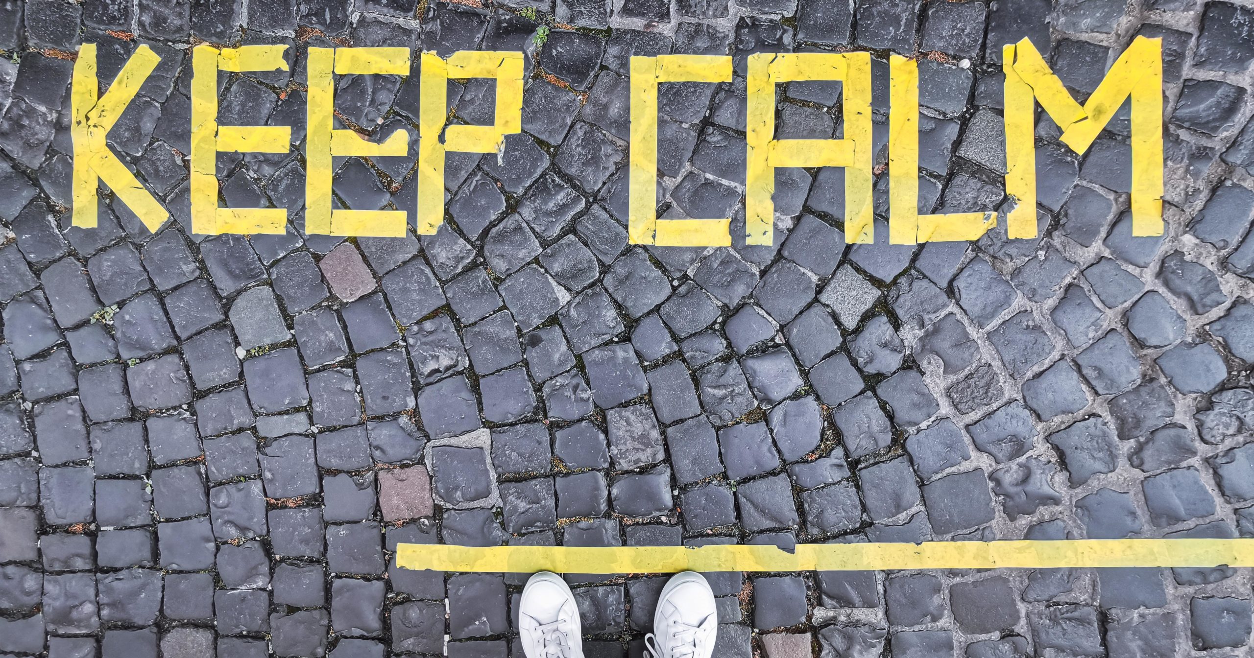 Gray cobblestone path with the words "Keep Calm" in yellow