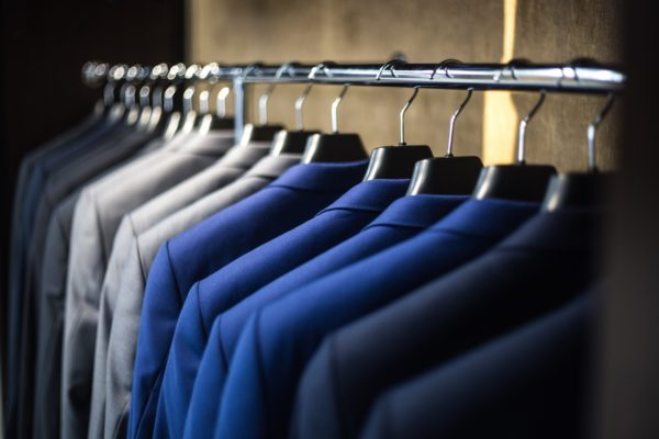 Organized blue and gray suit coats on hangers in a closet