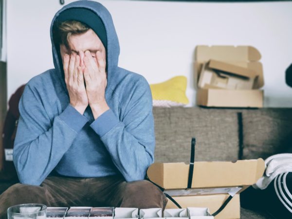 Stressed man in blue hoodie rubbing his face