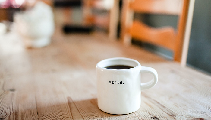 A white coffee mug with the word "begin" on it