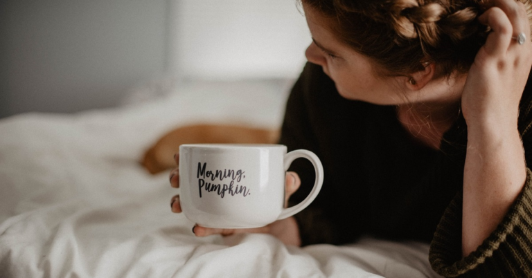 Woman in bed with a white coffee mug