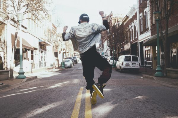 Guy jumping in the street with arms raised