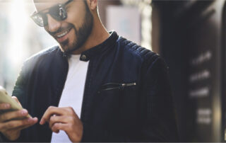 Man in sunglasses smiling and using smartphone