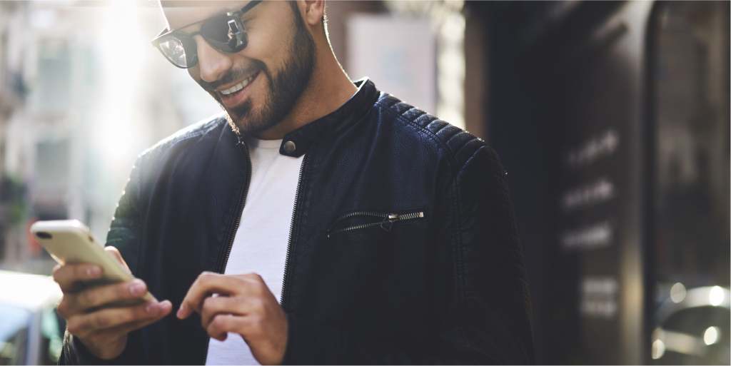 Man in sunglasses smiling and using smartphone