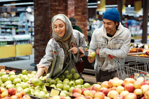 Woman and man shopping for apples at the grocery store and smiling