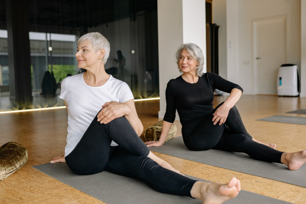 Two older women stretching on yoga mats